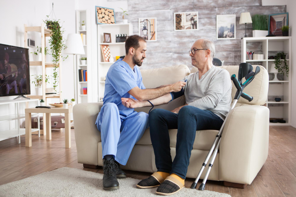 assisted living facility A man on a couch with a nurse holding his arm. Illustrates the topic of starting an assisted living facility.